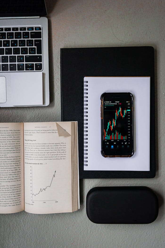 Top view of a workspace with financial tools featuring a smartphone showing stock charts.